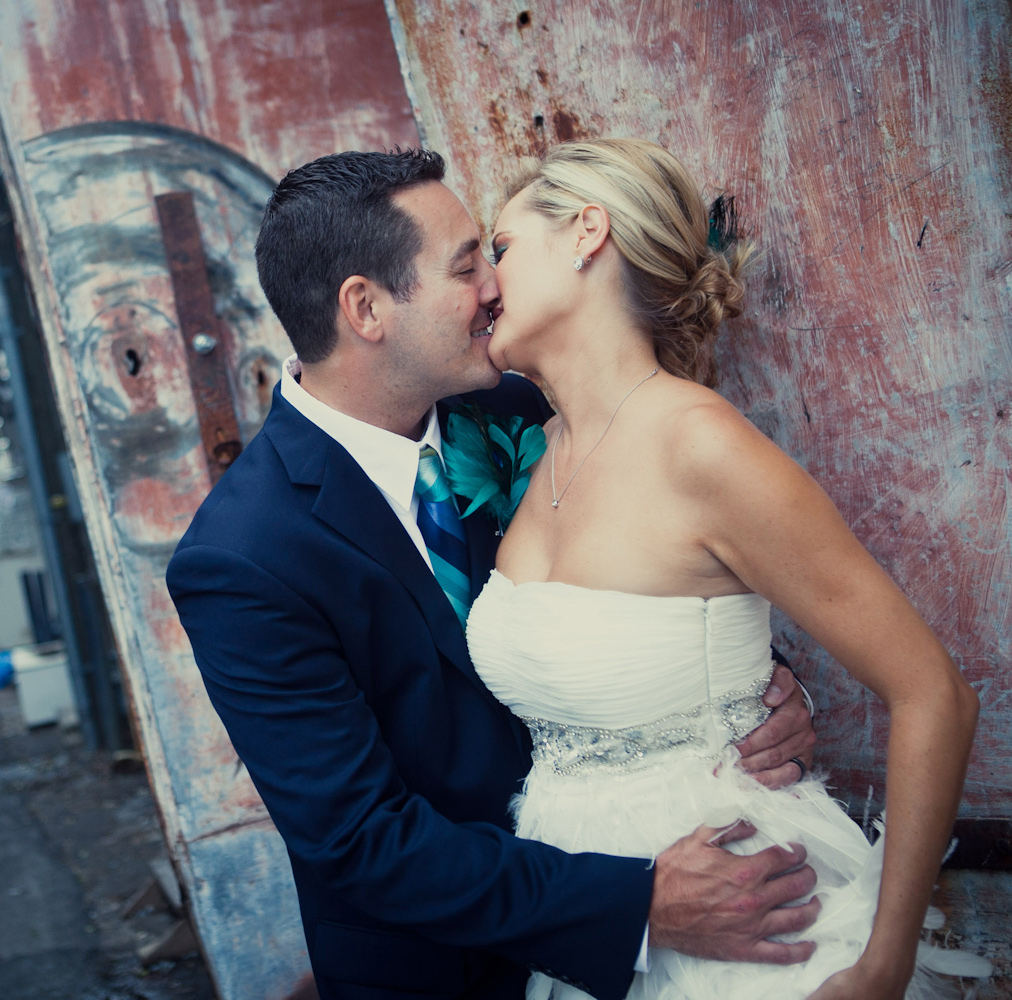bride and groom kissing along a alleyway